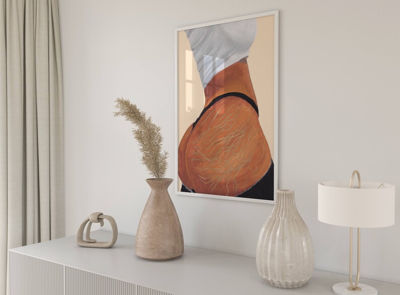 May include: A framed print of a painting depicting a woman's back with visible stretch marks. The painting is in a white frame and is hanging on a white wall.