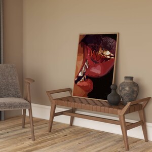 May include: A framed art print featuring a close-up of lips with gold teeth. The artwork uses shades of red, brown, and black. The print is displayed on a wooden bench with a woven leather seat, next to decorative vases.