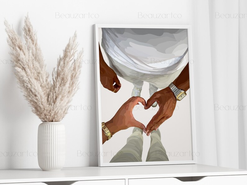 May include: A framed art print featuring a couple's hands forming a heart shape. The artwork depicts two people, with one wearing a gold watch and bracelet. The background is a neutral color, and the print is displayed on a white shelf.
