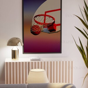 May include: A framed print of a basketball going through a hoop. The basketball is orange and the hoop is red. The background is a gradient of purple, pink, and orange.