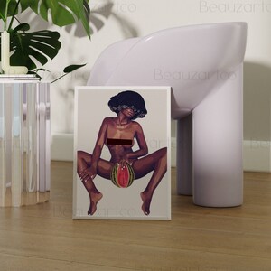 May include: A framed print of a digital illustration of a woman with dark skin and curly hair sitting with a watermelon in her lap. The woman is nude and the watermelon is red and green.