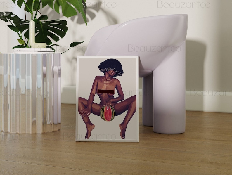 May include: A framed print of a digital illustration of a woman with dark skin and curly hair sitting with a watermelon in her lap. The woman is nude and the watermelon is red and green.