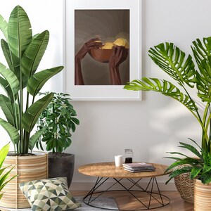 May include: A framed illustration of two hands holding a bowl of fruit. The hands are brown and the fruit is yellow. The background is a muted brown color. The frame is white and the illustration is in a minimalist style.