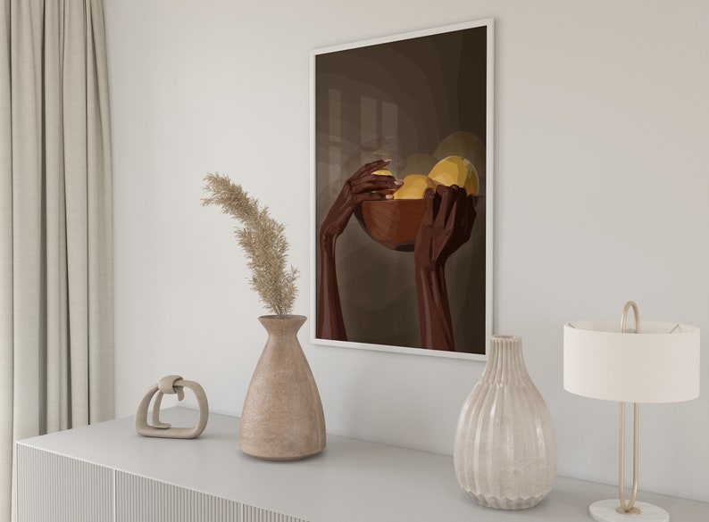 May include: A framed print of a stylized illustration of two hands holding a bowl of fruit. The hands are brown and the fruit is yellow. The background is a dark brown color.