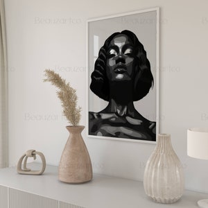 May include: Black and white illustration of a woman's face with her eyes closed. The illustration is framed and hanging on a white wall.