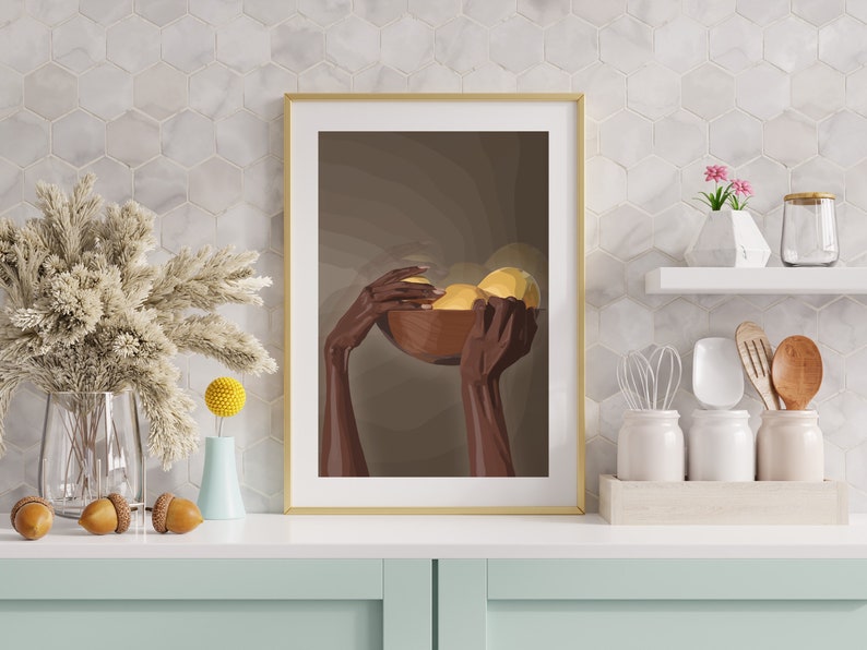 May include: A framed print of a pair of hands holding a wooden bowl filled with yellow fruit. The background is a muted brown color.