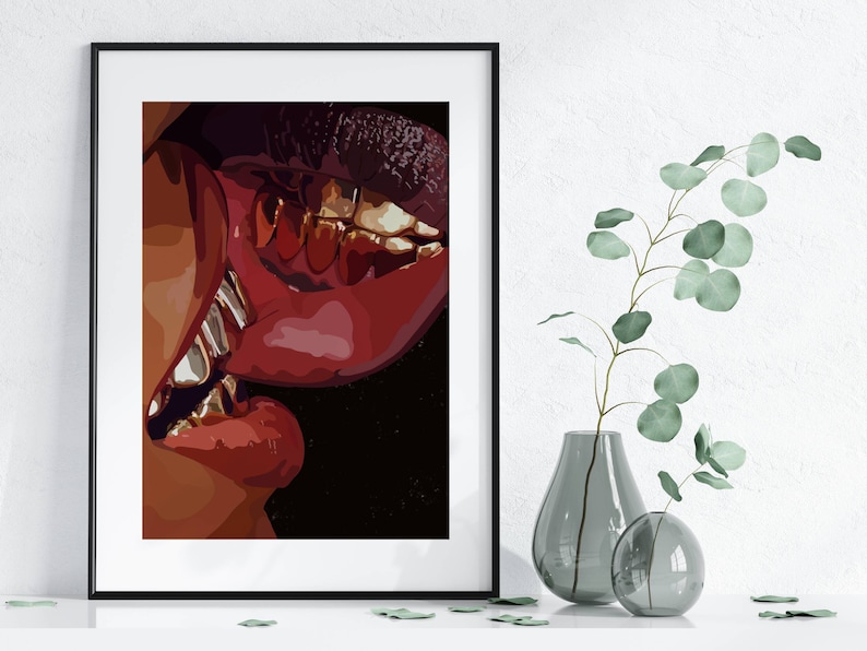May include: A framed art print featuring a close-up of two sets of lips in a kiss. The lips are a deep red with gold teeth. The artwork is set against a black background.