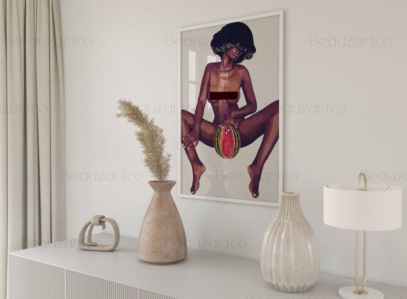 May include: A framed illustration of a woman with dark skin and short, curly hair. She is sitting with her legs spread and holding a watermelon in her lap. The background is a light gray color.