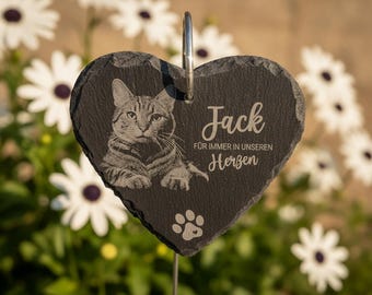Puede incluir: Una placa conmemorativa de pizarra gris oscuro en forma de corazón con el retrato grabado de un gato, una huella y el texto Jack FÜR IMMER IN UNSEREN Herzen. La placa incluye un gancho de metal plateado en la parte superior para colgar.