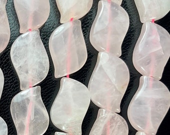May include: A strand of pale pink rose quartz beads, each bead is carved in a leaf shape. The beads are strung on a pink elastic cord.
