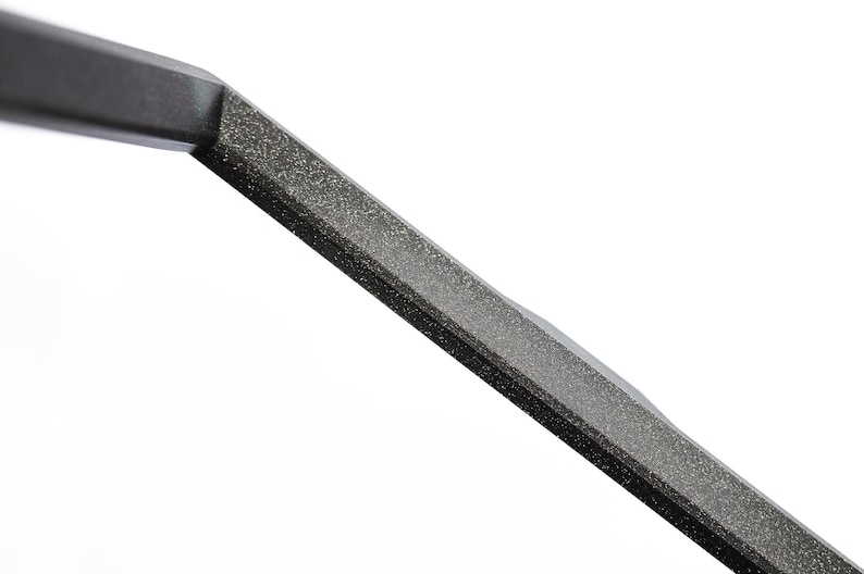 May include: Close-up of a black metal bar with a textured surface.