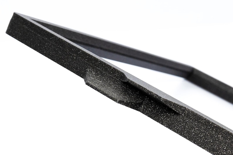 May include: Close-up of a black foam frame with a textured surface. The frame is made of a thick, durable material and has a simple, modern design.
