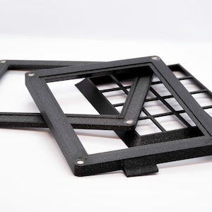 May include: Three black plastic frames with a grid pattern. The frames are stacked on top of each other.