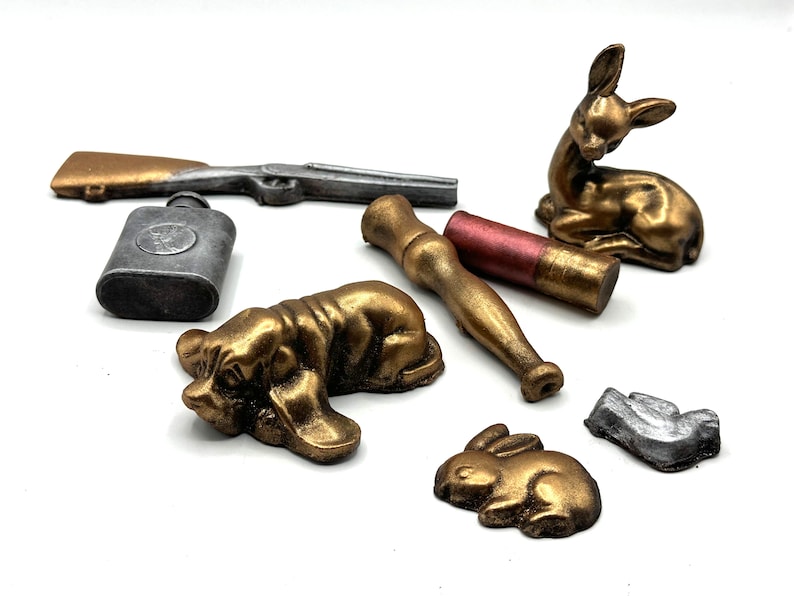 Pu&ograve; includere: Una collezione di figurine in miniatura, tra cui un cervo, due cani e un coniglio, tutti dipinti in oro e argento. C'&egrave; anche una piccola fiaschetta d'argento e un fucile dipinto in oro.