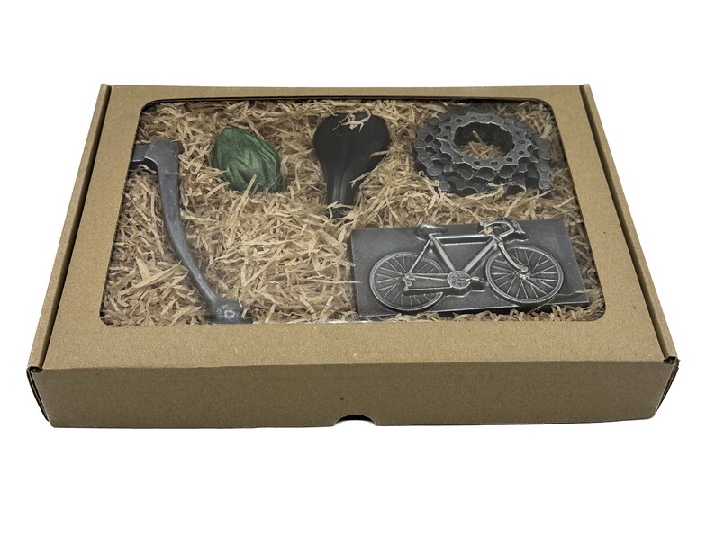 May include: A brown cardboard box with a clear window showing a set of five metal bicycle-themed gifts. The gifts include a bicycle chain, a bicycle seat, a bicycle handlebar, a bicycle wheel, and a bicycle silhouette.