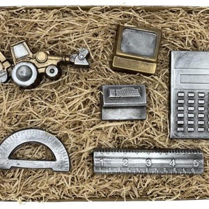 Könnte beinhalten: Ein Set aus sechs silbernen und goldenen Miniaturwerkzeugen in einer mit braunem Papier gefüllten Schachtel. Die Werkzeuge umfassen einen Bulldozer, einen Computer, einen Taschenrechner, einen Winkelmesser, ein Lineal und eine Tastatur.