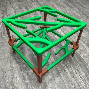 Könnte beinhalten: Ein quadratischer Tisch aus 3D-gedrucktem Kunststoff mit einem Labyrinth-Muster auf der Oberseite. Der Tisch ist grün und braun.