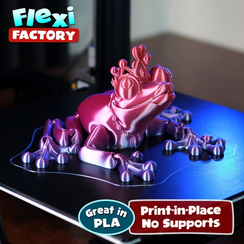 May include: A 3D printed pink and purple frog wearing a crown. The frog is printed in place with no supports needed. The text "Great in PLA" and "Print-in-Place No Supports" is visible in the image.