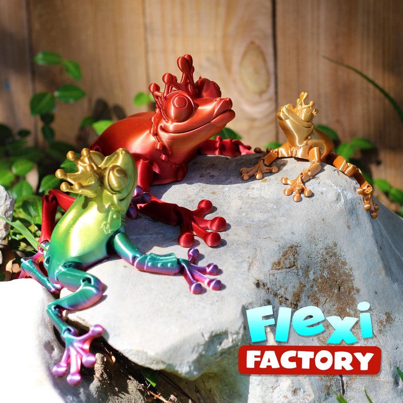 May include: Three 3D printed frog figurines with articulated limbs. The frogs are wearing crowns and are painted in metallic gold, red, and green.