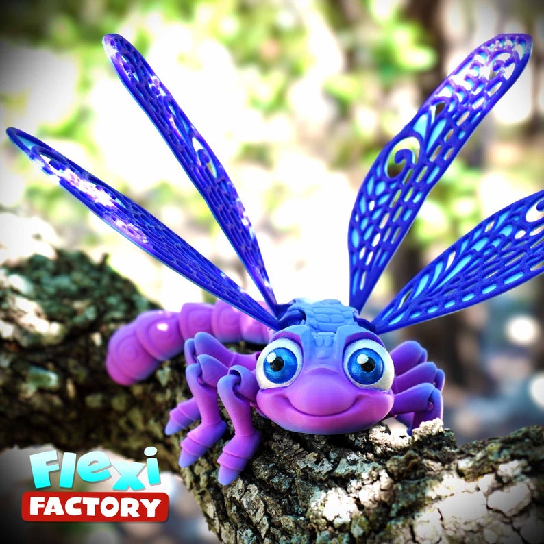 May include: A 3D-printed, articulated dragonfly toy in shades of purple and blue, perched on a tree branch. The dragonfly has large, detailed wings and a smiling face. The Flexi Factory logo is visible.