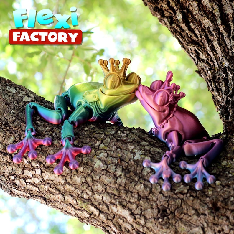 May include: Two iridescent frogs with crowns on their heads are kissing on a tree branch. The frog on the left is green, yellow, and blue. The frog on the right is pink, purple, and blue. The text "Flexi Factory" is visible in the top left corner of the image.