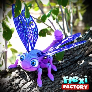 May include: A purple and blue dragonfly toy with large eyes and articulated legs and wings. The dragonfly is perched on a tree branch. The wings are a vibrant blue with a detailed, openwork design. The logo "Flexi Factory" is visible.