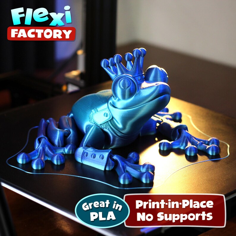 May include: A blue 3D printed frog wearing a crown, with articulated legs and a print-in-place design. The frog is printed on a 3D printer bed, with the text "Great in PLA Print-in-Place No Supports" visible below the frog.