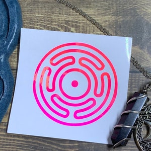 May include: A silver necklace with a triple moon pendant and a tree of life design. The pendant also features a pentagram and a circle with a Celtic knot design. The necklace is displayed with a pink and white sticker with a circular symbol and a black and purple crystal.