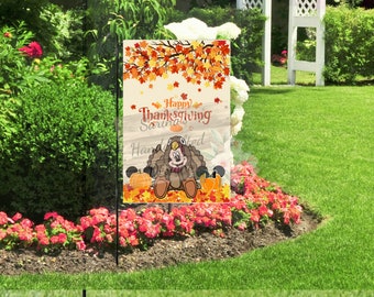 May include: A garden flag featuring a cartoon turkey dressed in a Thanksgiving outfit. The flag has the words "Happy Thanksgiving" and "Handmade" on it. The background has autumn leaves and pumpkins.