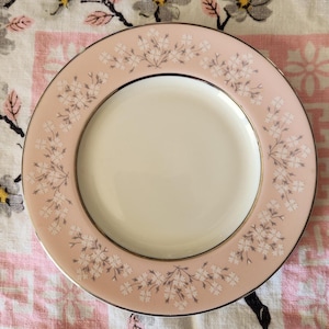 May include: A pink and white floral patterned ceramic plate with a gold rim.