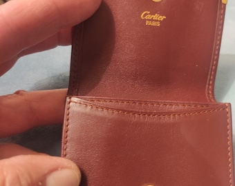 Cartier coin purse made of the characteristic burgundy leather the accessories are in gold color and inside with cartier paris authentic