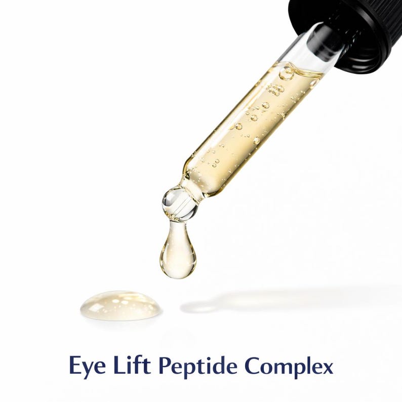 May include: A close-up of a glass dropper dispensing a clear, amber-colored liquid. A single drop of the liquid is falling, with a small puddle on the white surface. The text "Eye Lift Peptide Complex" is at the bottom.