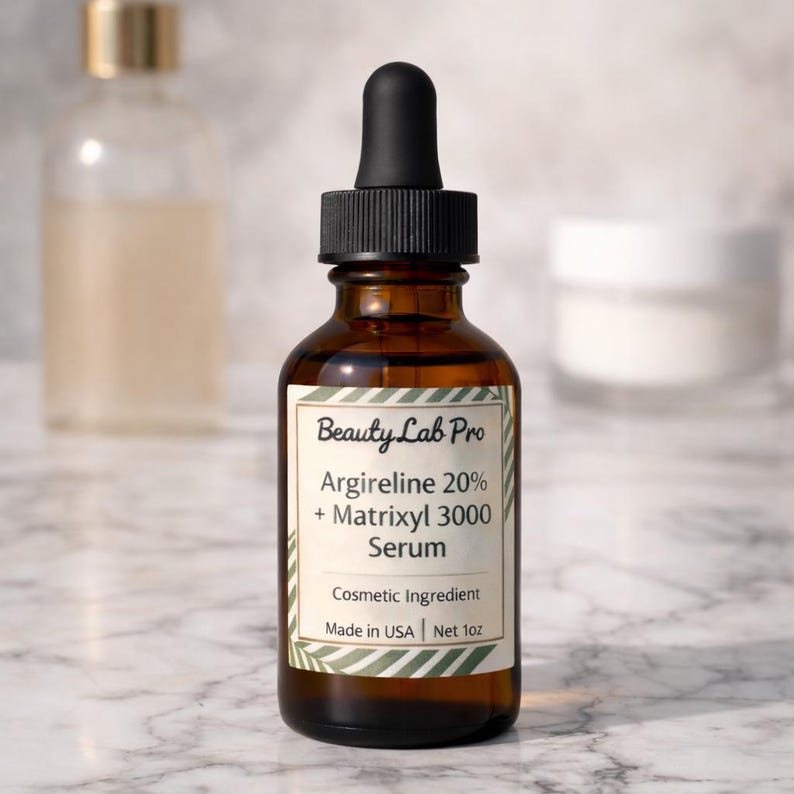 以下が含まれることがあります： 黒いスポイトが付いた、Beauty Lab Proセラムの茶色のガラス瓶。「Argireline 20% + Matrixyl 3000 Serum」と「Made in USA | Net 1oz」と書かれたラベル。大理石の表面にボトルが置かれています。