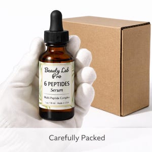 Peut inclure: Une bouteille en verre marron de s&eacute;rum Beauty Lab Pro 6 Peptides, tenue dans une main gant&eacute;e, avec un compte-gouttes noir et une &eacute;tiquette blanche. L'&eacute;tiquette indique "Multi-Peptide Complex" et "1 oz/30 ml Made in USA". Une bo&icirc;te en carton marron est en arri&egrave;re-plan.