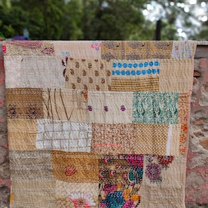 Può includere: Un quilt patchwork realizzato con diversi tessuti in tonalità di marrone, blu, verde e rosa. Il quilt è composto da quadrati e rettangoli di diverse dimensioni e motivi. Il quilt è cucito a mano e ha un aspetto rustico e vintage.