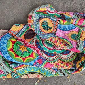 Puede incluir: Una colcha de retazos colorida con una variedad de patrones y dise&ntilde;os, incluyendo c&iacute;rculos, flores y formas geom&eacute;tricas. La colcha est&aacute; hecha de tela de algod&oacute;n y est&aacute; cosida a mano.
