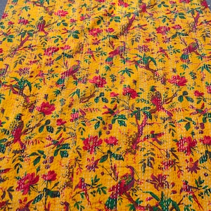 May include: A yellow kantha quilt with a floral and bird pattern. The quilt features red flowers, green leaves, and brown birds.