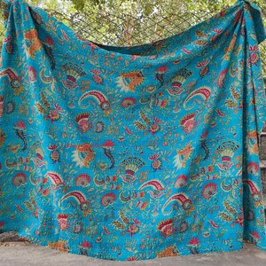 K&ouml;nnte beinhalten: Eine t&uuml;rkisblaue Kantha-Steppdecke mit einem floralen Muster in Rosa-, Gelb- und Gr&uuml;nt&ouml;nen. Die Steppdecke ist aus Baumwolle und handgen&auml;ht.