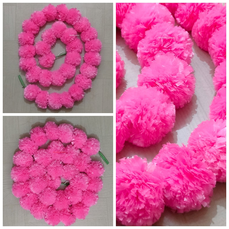 May include: A garland of pink paper flowers, arranged in a circle. The garland is made of multiple layers of paper flowers, creating a full and fluffy look.