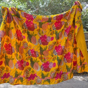 Op de afbeelding: Een gele kantha-deken met een bloemenpatroon in tinten roze, groen en bruin. De deken is gemaakt van katoen en met de hand gestikt.