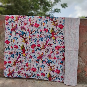 May include: White kantha quilt with a floral and bird pattern. The quilt is made of cotton and has a hand-stitched design. The quilt is perfect for adding a touch of bohemian style to your home.