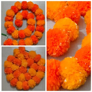 May include: A garland of orange and yellow marigold flowers made from tissue paper. The garland is made up of individual flower pom-poms.