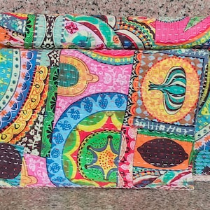 Puede incluir: Una colcha de retazos colorida con una variedad de patrones, incluyendo dise&ntilde;os de paisley, florales y geom&eacute;tricos. La colcha est&aacute; hecha de tela de algod&oacute;n y est&aacute; cosida a mano. La colcha est&aacute; doblada por la mitad y est&aacute; sobre una superficie de piedra.