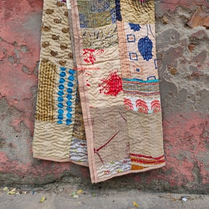 May include: A patchwork quilt made from repurposed fabric scraps. The quilt is beige with brown, blue, red, and green accents. The quilt is hand-stitched and has a unique, rustic look.