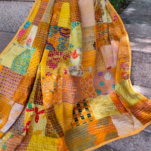 May include: A yellow, brown and purple patchwork quilt with a kantha stitch pattern. The quilt is made from recycled saris and is hand-stitched.