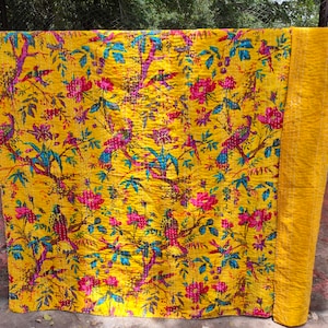 May include: A yellow kantha quilt with a floral and bird pattern. The quilt is made of cotton and is hand-stitched. It is a traditional Indian textile.