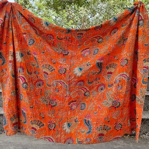 K&ouml;nnte beinhalten: Orangefarbene Kantha-Steppdecke mit floralem und Paisley-Muster. Die Decke ist aus Baumwolle und handgen&auml;ht.