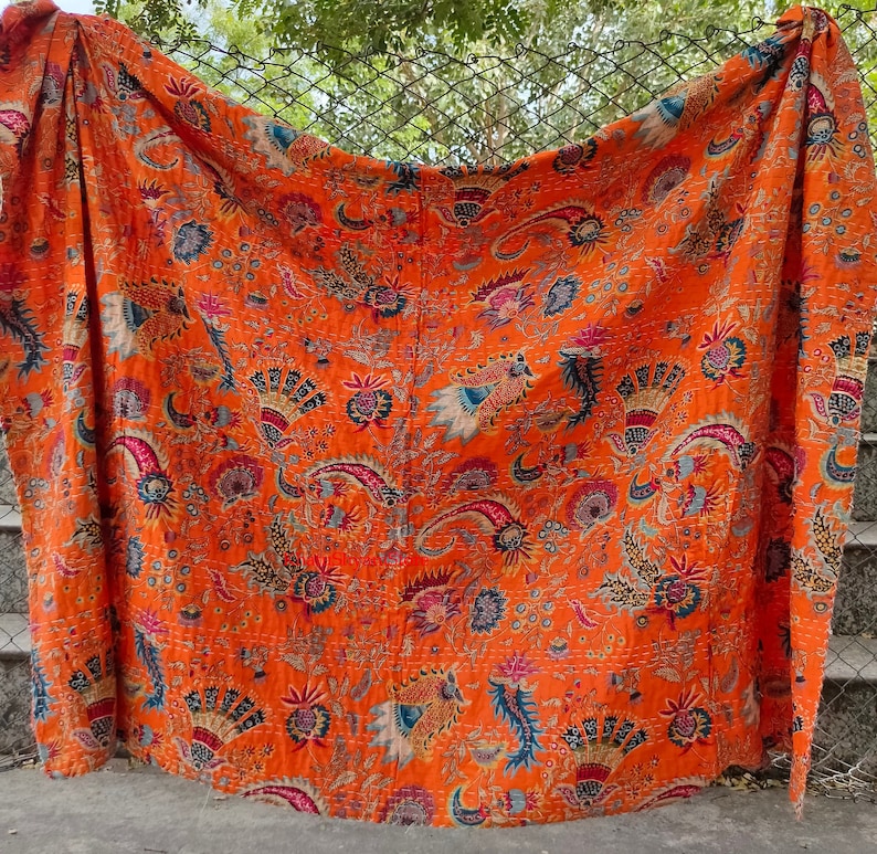K&ouml;nnte beinhalten: Orangefarbene Kantha-Steppdecke mit floralem und Paisley-Muster. Die Decke ist aus Baumwolle und handgen&auml;ht.