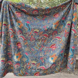 K&ouml;nnte beinhalten: Eine blaue Kantha-Steppdecke mit einem floralen Muster in Rot-, Gelb- und Gr&uuml;nt&ouml;nen. Die Steppdecke ist aus Baumwolle und handgen&auml;ht.