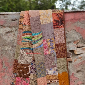 May include: A patchwork quilt made from repurposed fabric scraps in shades of brown, beige, and orange. The quilt is hand-stitched and has a rustic, vintage look.